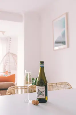 a bottle of wine sitting on a table with a glass at Pentire Point - Fully Equipped Eco Escape in Crantock