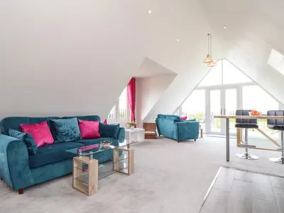 a living room with a blue couch and a table at Higher Kernick View in Bodmin