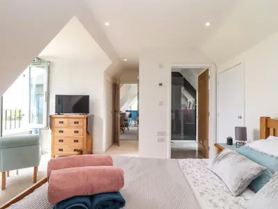 a bedroom with a bed and a chair and a television at Higher Kernick View in Bodmin