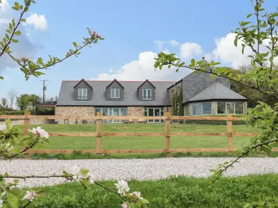 a house with a wooden fence and a yard at Higher Kernick View in Bodmin