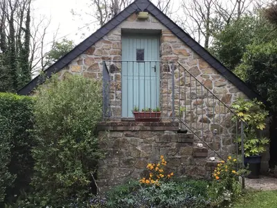 a small stone house with a blue door and stairs at Cozy Camborne Studio Retreat with two single beds in Camborne