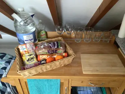 a table with a basket of food and wine glasses at Cozy Camborne Studio Retreat with two single beds in Camborne