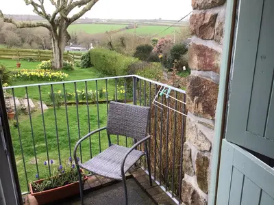 a chair sitting on a balcony with a garden at Cozy Camborne Studio Retreat with two single beds in Camborne