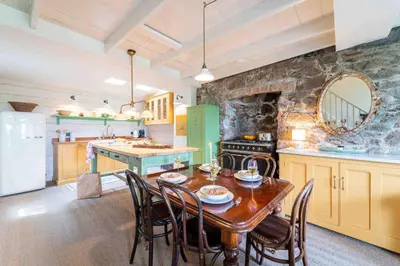 a kitchen with a table and chairs and a stone wall at Secret Cottage in St Ives