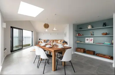 a dining room with a wooden table and white chairs at The Old Coastguard Lookout in Port Isaac