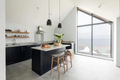 a kitchen with black cabinets and a large window at The Old Coastguard Lookout in Port Isaac