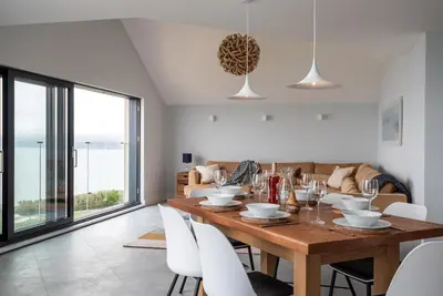 a dining room with a wooden table and white chairs at The Old Coastguard Lookout in Port Isaac