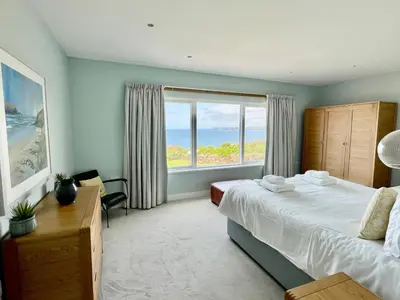 a bedroom with a bed and a large window at The Old Coastguard Lookout in Port Isaac