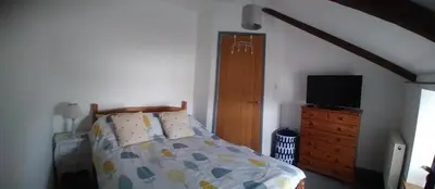 a bedroom with a bed and a dresser with a television at Sam's retreat in Hayle