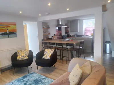 a living room and kitchen with a couch and chairs at Sam's retreat in Hayle
