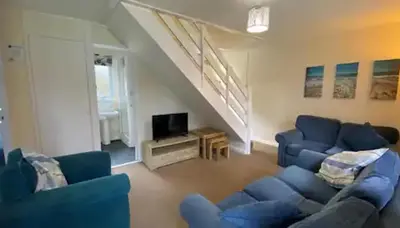 a living room with blue couches and a staircase at Trevithick Cottage Sleeps 6 Dog Friendly Parking in Hayle