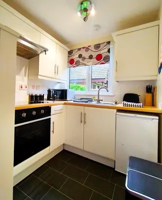 a kitchen with white cabinets and a sink and a window at Trevithick Cottage Sleeps 6 Dog Friendly Parking in Hayle