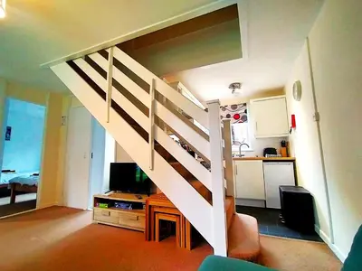 a white staircase in a living room with a kitchen at Trevithick Cottage Sleeps 6 Dog Friendly Parking in Hayle