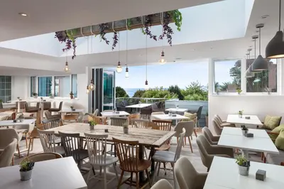 a restaurant with tables and chairs and large windows at St Michaels The Liner in Falmouth
