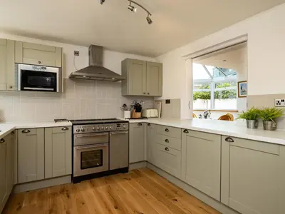a kitchen with white cabinets and a stove top oven at Lamorna in Port Isaac