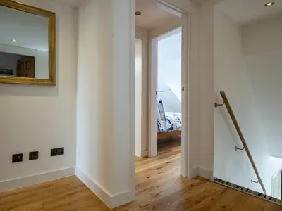 a hallway with white walls and a mirror and a staircase at Lamorna in Port Isaac