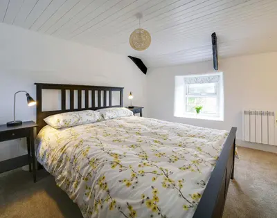 a bedroom with a large bed and a window at Dane Cottage in Port Isaac