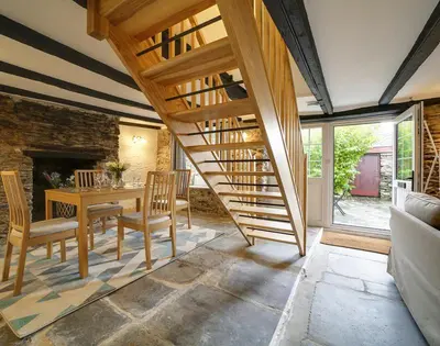 a living room with a staircase and a table and chairs at Dane Cottage in Port Isaac