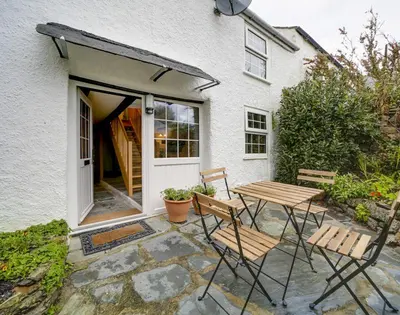 a patio with two chairs and a table in front of a house at Dane Cottage in Port Isaac