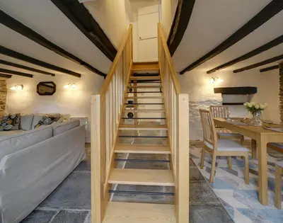 a staircase in a room with a couch and a table at Dane Cottage in Port Isaac
