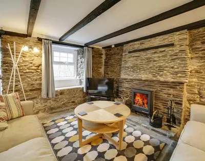 a living room with a table and a fireplace at Dane Cottage in Port Isaac
