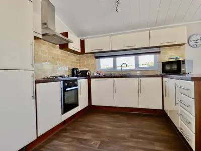 a kitchen with white cabinets and a stove top oven at 23 Bossiney Bay in Tintagel