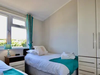 a bedroom with two beds and a window at 23 Bossiney Bay in Tintagel