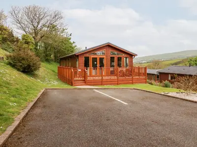 a large wooden house with a parking lot at 23 Bossiney Bay in Tintagel