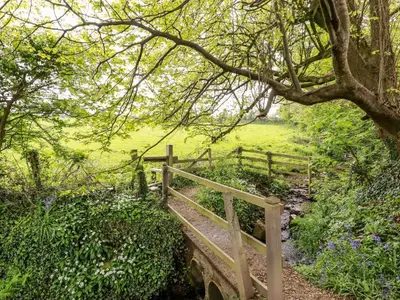 a wooden bridge in a field with a fence at 23 Bossiney Bay in Tintagel