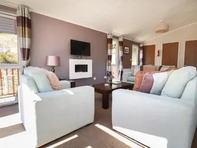 a living room with two white chairs and a table at 23 Bossiney Bay in Tintagel