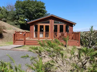 a small cabin with a large deck on a hill at 23 Bossiney Bay in Tintagel