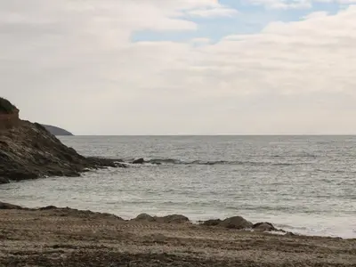 a beach with rocks and the ocean on a cloudy day at Blackbird Cottage in Falmouth
