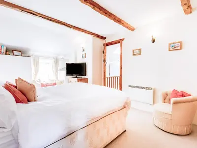 a bedroom with a large bed and a chair at Temple Cottage in Port Isaac