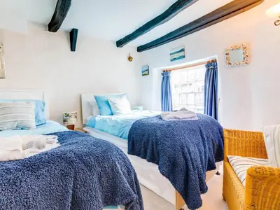 a bedroom with two beds and a window at Temple Cottage in Port Isaac