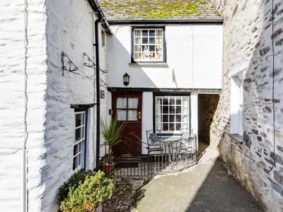 an old white house with a red door at Temple Cottage in Port Isaac