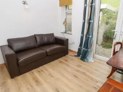 a brown leather couch in a living room with a table at Penmarth House in Helston