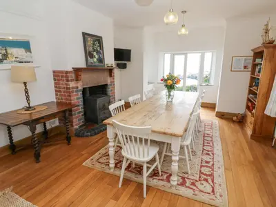 a dining room with a table and chairs and a fireplace at Penmarth House in Helston