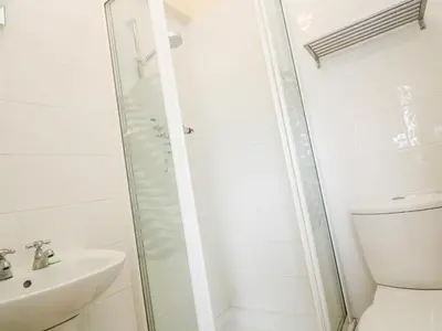 a bathroom with a shower and a toilet and a sink at Penmarth House in Helston