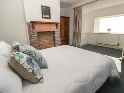 a bedroom with a bed and a brick fireplace at Penmarth House in Helston
