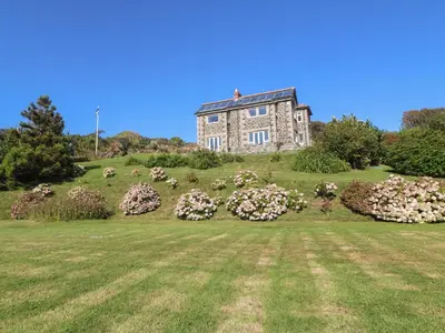 an old house on top of a hill with flowers at Penmarth House in Helston