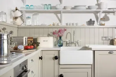 a kitchen with white cabinets and a sink at Carvossa - Sea Views & Woodburner in Marazion