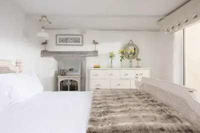 a white bedroom with a white bed and a dresser at Carvossa - Sea Views & Woodburner in Marazion