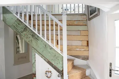a staircase in a house with a green railing at Carvossa - Sea Views & Woodburner in Marazion