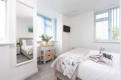 a white bedroom with a bed and a mirror at Kingsley House - Free Parking & WiFi - Close to Newquay's Beaches in Newquay