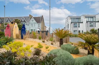 a garden with surfboards and plants in front of houses at Kingsley House - Free Parking & WiFi - Close to Newquay's Beaches in Newquay
