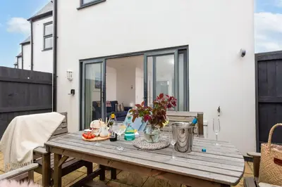 a wooden table with flowers on a patio at Kingsley House - Free Parking & WiFi - Close to Newquay's Beaches in Newquay