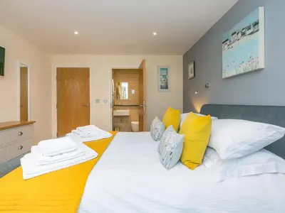a bedroom with a large white bed with yellow pillows at Golden Sands in St Ives
