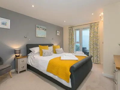 a bedroom with a bed with a yellow blanket on it at Golden Sands in St Ives