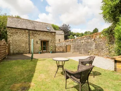 a table and chairs in the yard of a stone building at Miller's Lodge in Liskeard