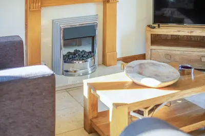a living room with a table and a fireplace at Miller's Lodge in Liskeard